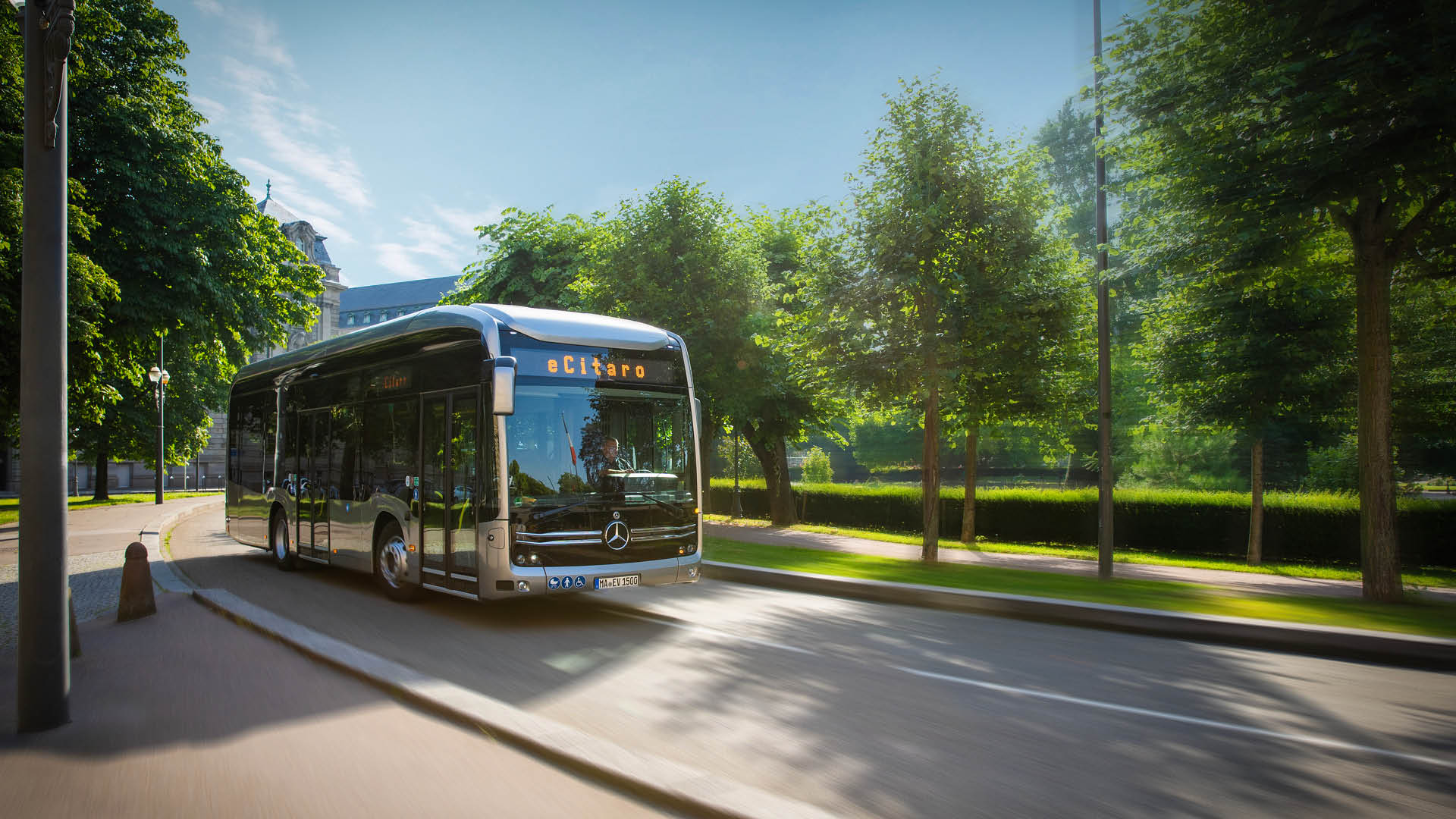 Elektrisk Mercedes-Benz eCitaro-buss från Daimler kör längs en grönskande stadsgata.