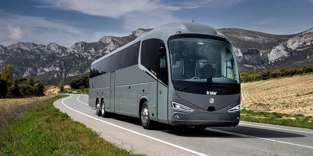 Irizar_1080x540px Grey Irizar coach travelling along a country road with a mountainous landscape in the background.